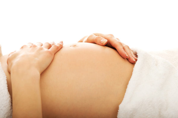 Pregnant woman massagin her growing belly